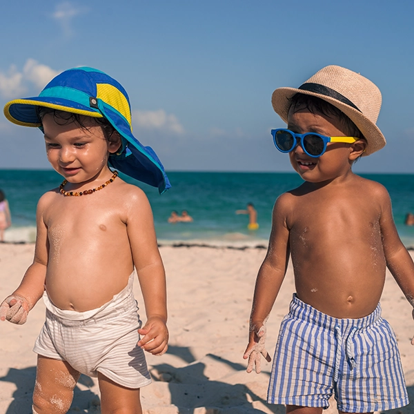 Kinder mit Hut und Kappe am Strand