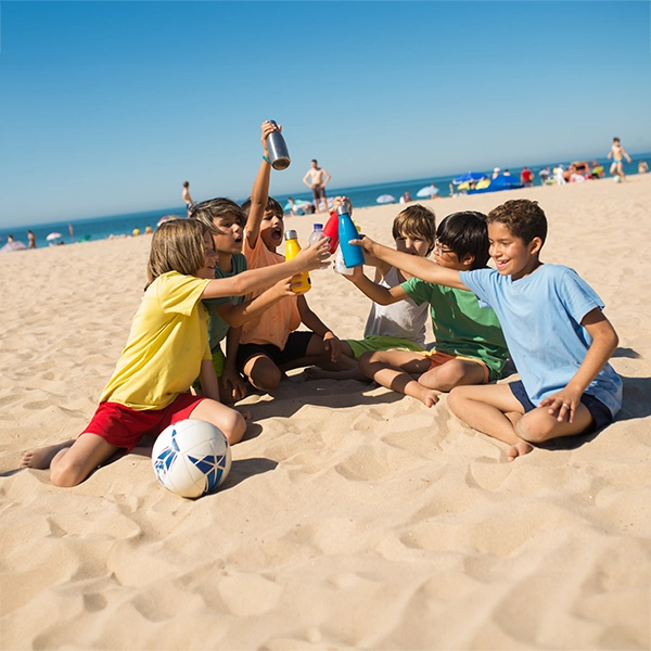 Kinder am Strand trinken Wasser